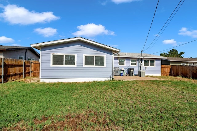 rear view of house featuring a fenced backyard, a yard, and central AC