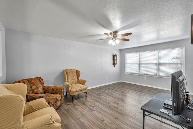 interior space with baseboards, a ceiling fan, a textured ceiling, and wood finished floors