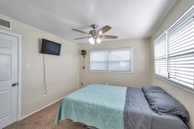 carpeted bedroom with baseboards, a ceiling fan, and visible vents