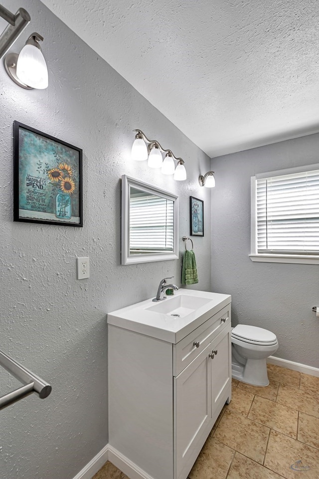 bathroom with toilet, a textured ceiling, baseboards, and vanity