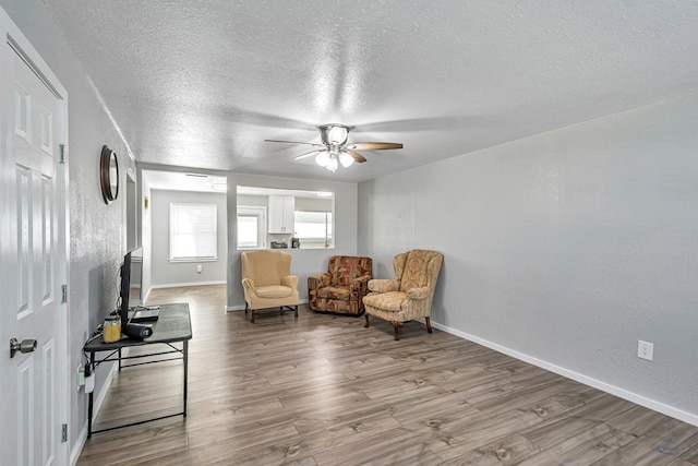 sitting room featuring baseboards, a ceiling fan, a textured ceiling, and wood finished floors