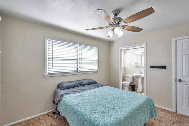 bedroom featuring baseboards, ceiling fan, connected bathroom, a sink, and carpet