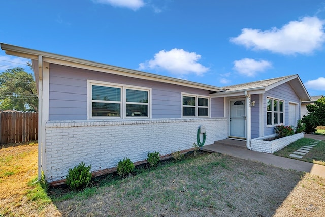 ranch-style house with brick siding, a front lawn, and fence