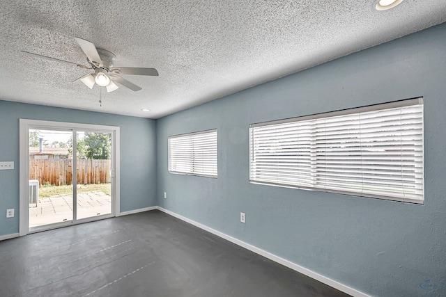 spare room with a ceiling fan, baseboards, finished concrete floors, and a textured ceiling