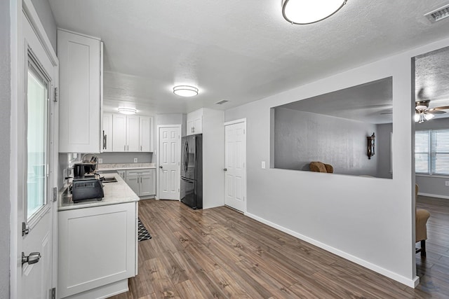 kitchen featuring white cabinets, dark wood-style flooring, light countertops, freestanding refrigerator, and visible vents
