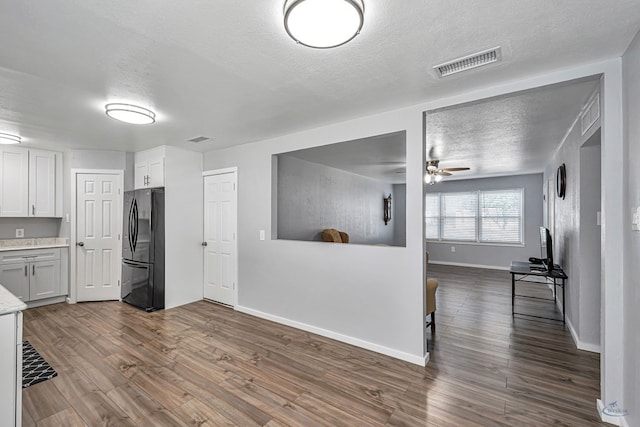 kitchen featuring freestanding refrigerator, a textured ceiling, visible vents, and dark wood-type flooring