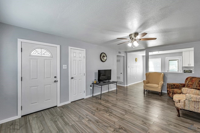 entryway with baseboards, a ceiling fan, a textured ceiling, and wood finished floors