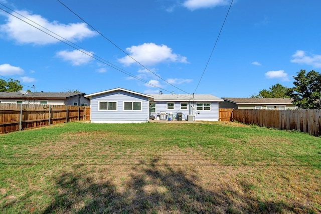rear view of house featuring a lawn and a fenced backyard