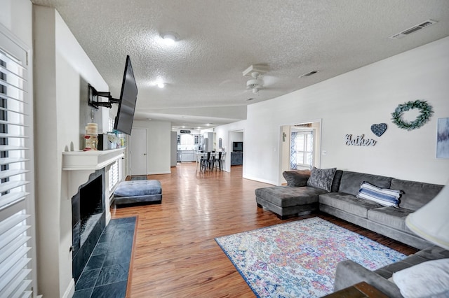 4107 Crestgate Ave, Midland, TX 79707 - living area with a textured ceiling, light wood finished floors, a fireplace with flush hearth, and ceiling fan