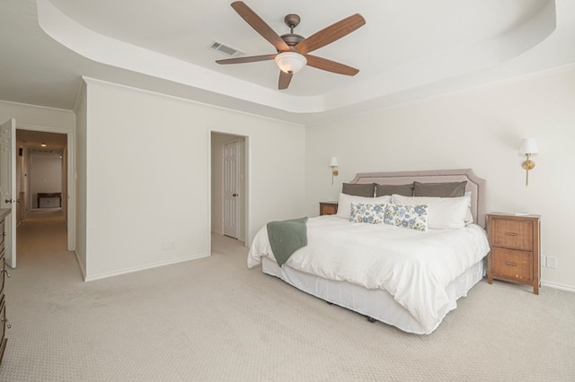 bedroom featuring light carpet, visible vents, baseboards, a tray ceiling, and crown molding