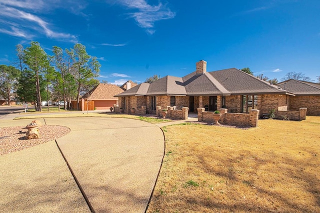 view of front of house featuring a front lawn, curved driveway, and a chimney