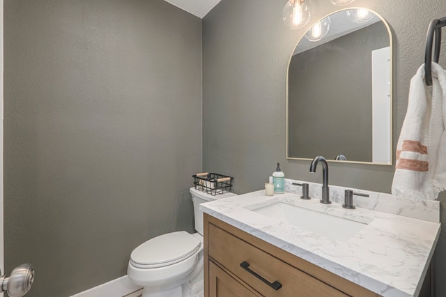 half bathroom with toilet, baseboards, and vanity