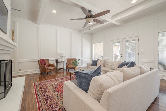 living room with visible vents, dark wood-type flooring, beamed ceiling, a fireplace, and a decorative wall