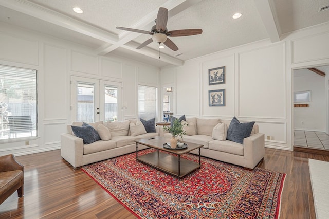 living area with beamed ceiling, wood finished floors, and a decorative wall