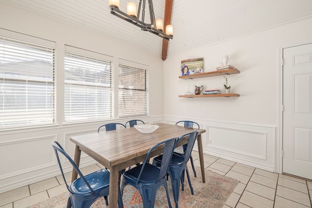 dining area featuring wainscoting, vaulted ceiling, a decorative wall, and light tile patterned floors