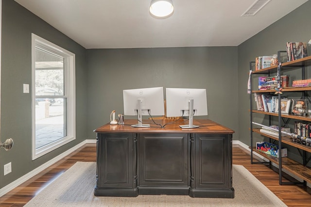 office with dark wood-style flooring, visible vents, and baseboards