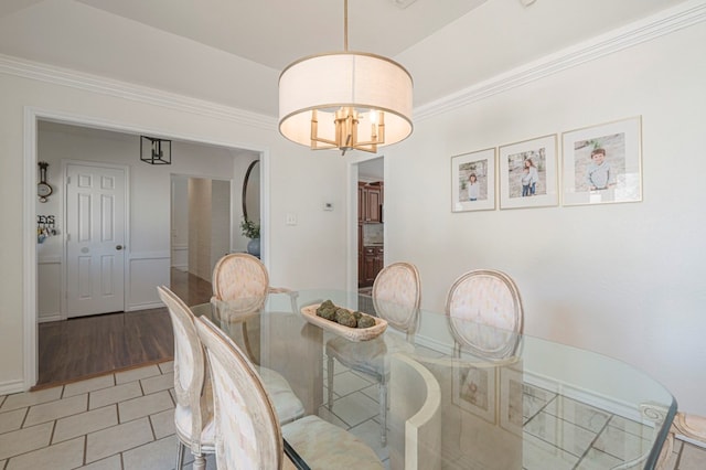 dining area with ornamental molding, light tile patterned floors, and an inviting chandelier