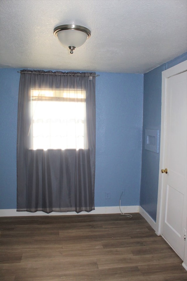 unfurnished room with a textured ceiling and dark wood-type flooring