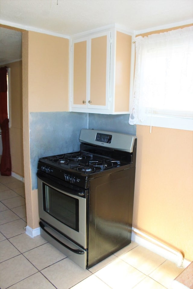 kitchen with white cabinets, light tile patterned floors, and stainless steel gas range