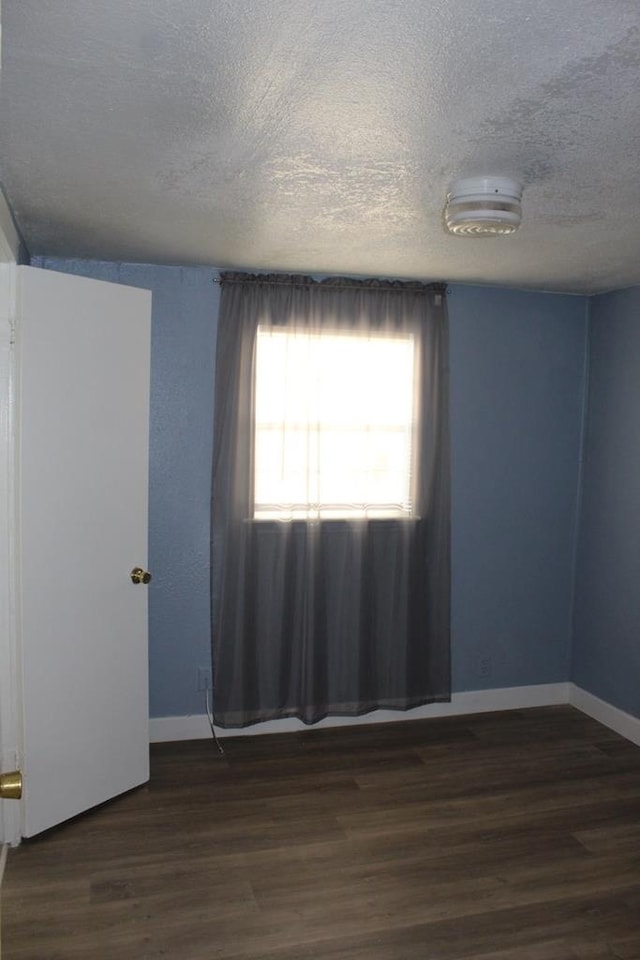 unfurnished room featuring a textured ceiling and dark hardwood / wood-style floors