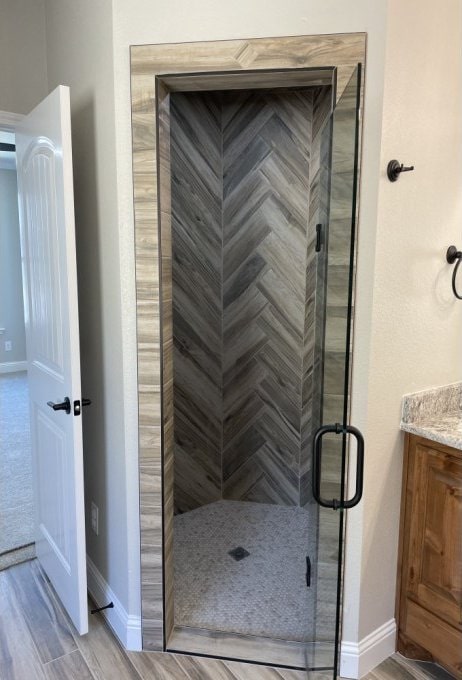 bathroom featuring vanity, wood finished floors, a stall shower, and baseboards