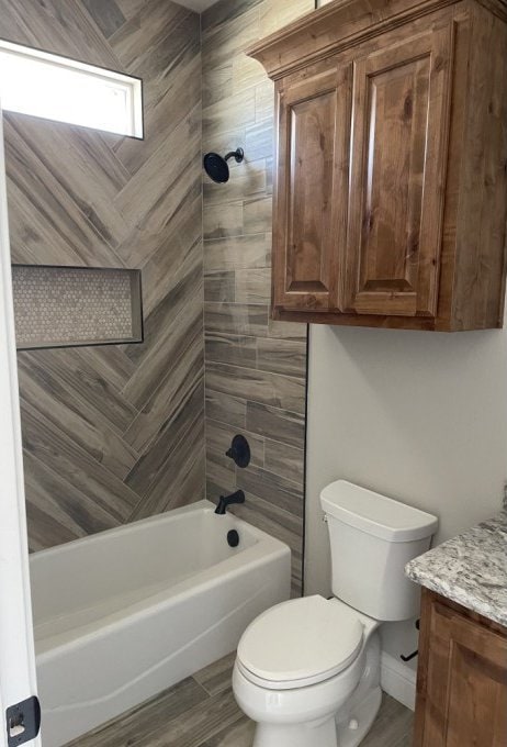 full bath featuring bathing tub / shower combination, toilet, wood finished floors, and vanity