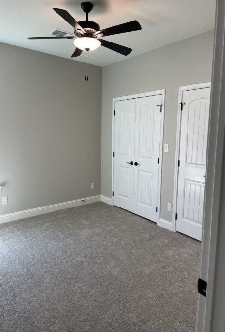 unfurnished bedroom featuring a closet, carpet flooring, a ceiling fan, and baseboards