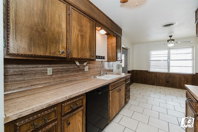 kitchen with wood walls, dishwasher, ceiling fan, and sink