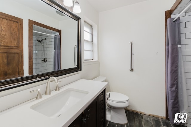 bathroom with a shower with shower curtain, hardwood / wood-style floors, vanity, and toilet