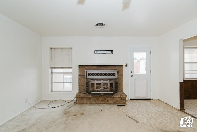 unfurnished living room with a wood stove and wood walls