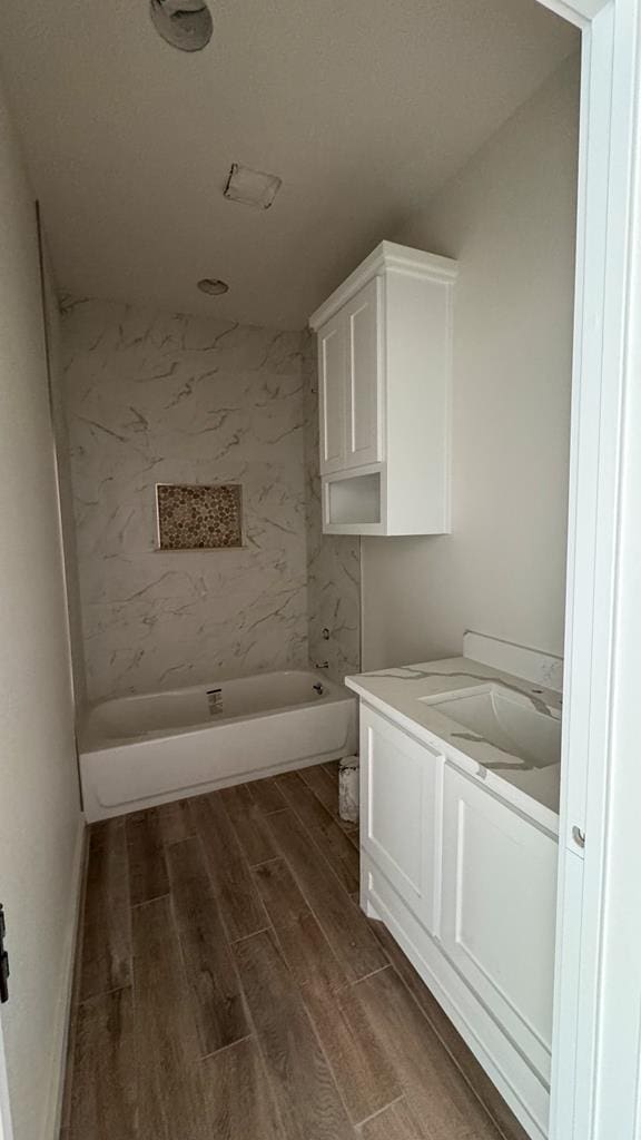 bathroom with vanity, wood-type flooring, and tiled shower / bath