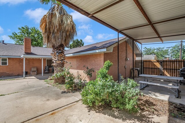 view of side of home with fence, a patio, and brick siding