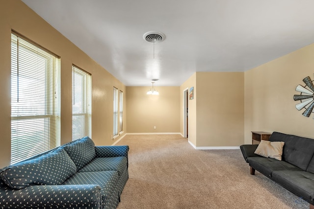 living room with carpet floors, an inviting chandelier, baseboards, and visible vents