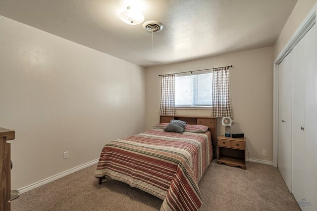 bedroom with baseboards, a closet, visible vents, and light colored carpet