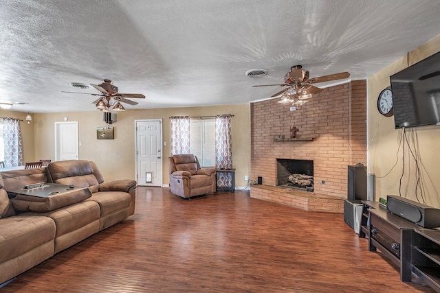 living room with a brick fireplace, wood finished floors, visible vents, and a ceiling fan