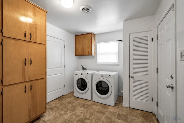 washroom featuring visible vents, cabinet space, washer and clothes dryer, and baseboards