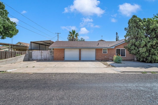 view of front facade with a garage, fence, concrete driveway, and brick siding