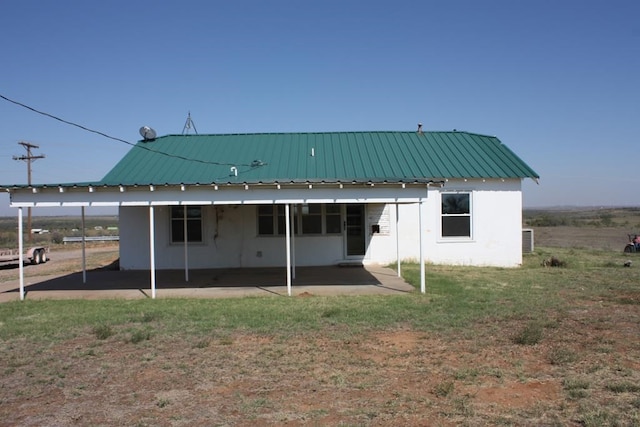 rear view of property featuring a patio area, metal roof, and a yard