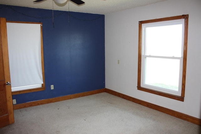 carpeted empty room with ceiling fan, baseboards, and a textured ceiling