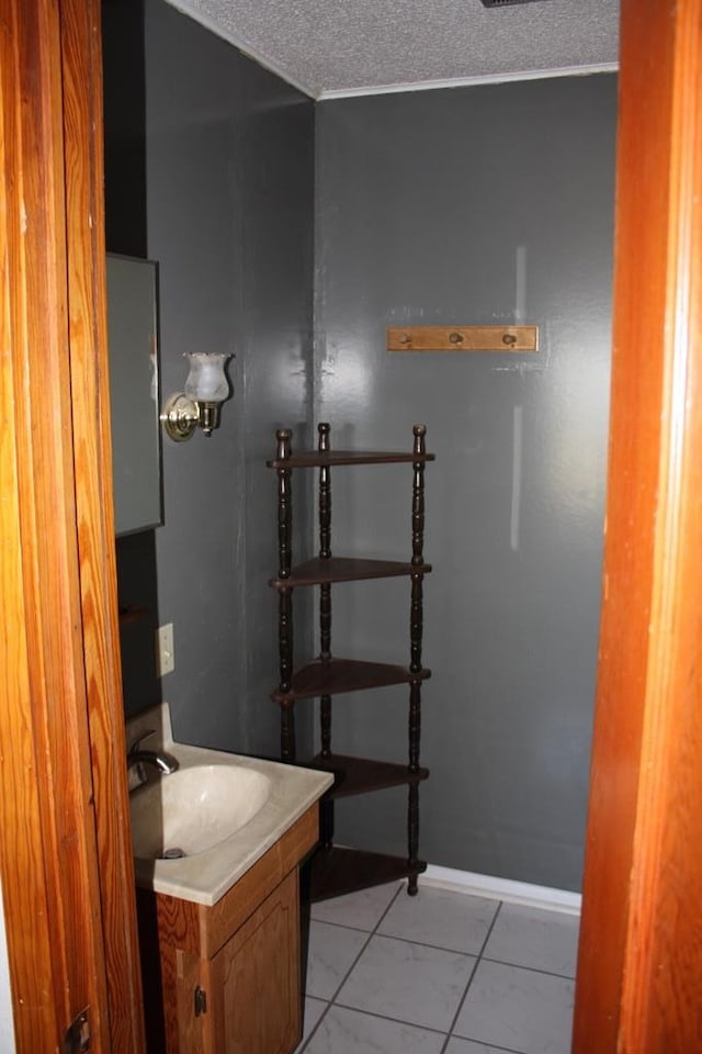 bathroom with tile patterned flooring, baseboards, a textured ceiling, and vanity