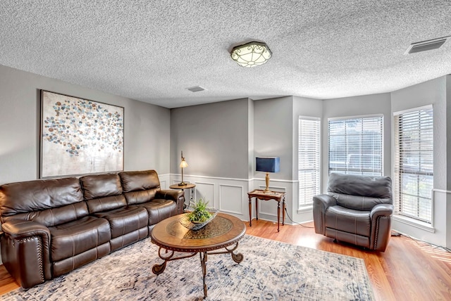 living room with a textured ceiling and light wood-type flooring