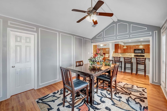 dining room with vaulted ceiling with beams, ceiling fan, and light wood-type flooring