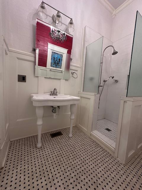 2311 30th St, Snyder, TX 79549 - bathroom with crown molding, a tile shower, a decorative wall, and wainscoting