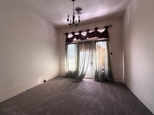 2311 30th St, Snyder, TX 79549 - spare room featuring a chandelier and carpet flooring