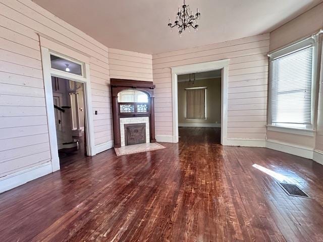 2311 30th St, Snyder, TX 79549 - unfurnished living room with wood-type flooring, a chandelier, wooden walls, and a fireplace