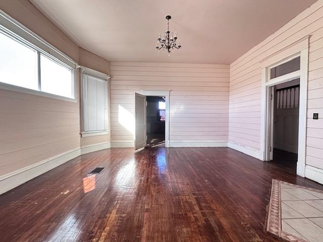 2311 30th St, Snyder, TX 79549 - empty room with wood-type flooring, a chandelier, and wooden walls