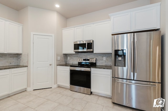 kitchen with white cabinets, stainless steel appliances, and dark stone countertops