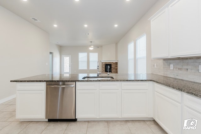 kitchen featuring white cabinets, a wealth of natural light, dark stone counters, and dishwasher