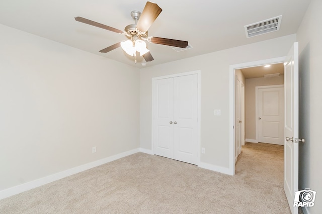 unfurnished bedroom featuring light colored carpet, a closet, and ceiling fan