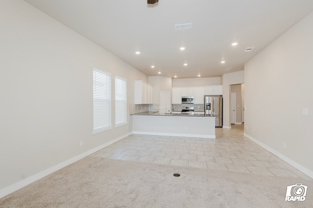 kitchen with white cabinets, backsplash, light tile patterned floors, kitchen peninsula, and stainless steel appliances